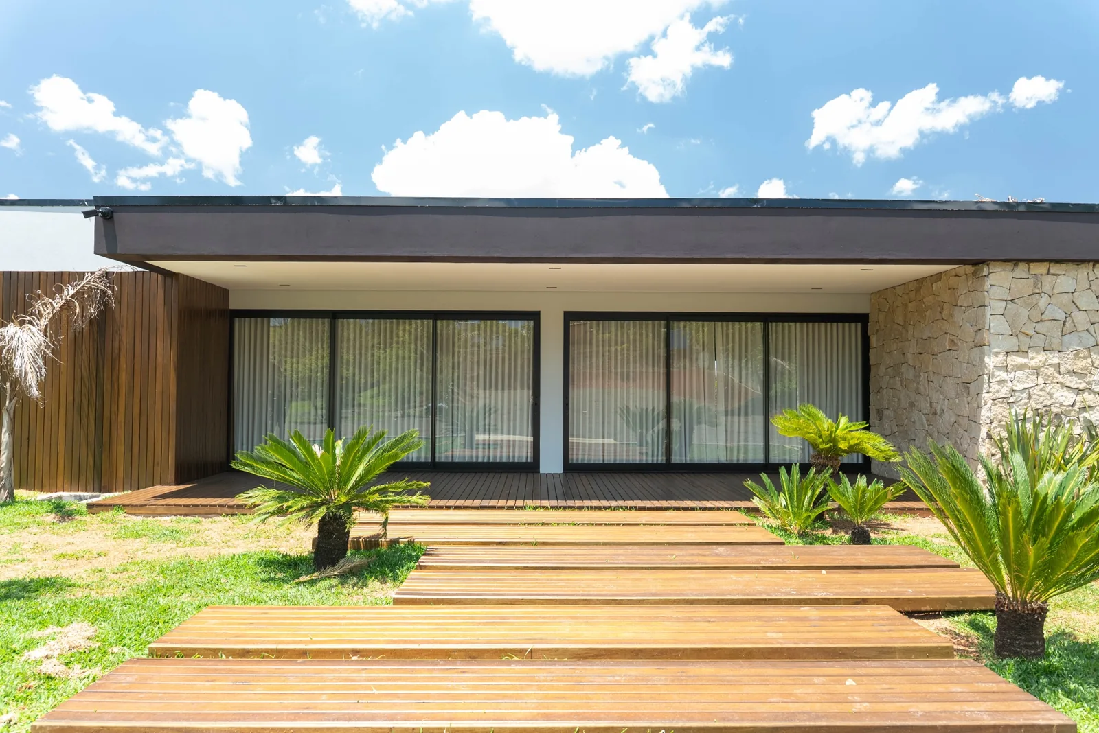 Fachada residencial com deck de madeira e pedra